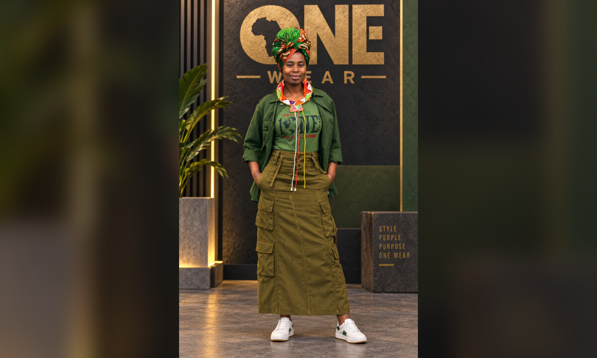 Model wearing a green One Wear outfit in a polished fashion campaign setting